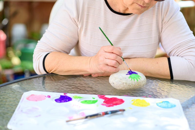 senior woman painting rocks